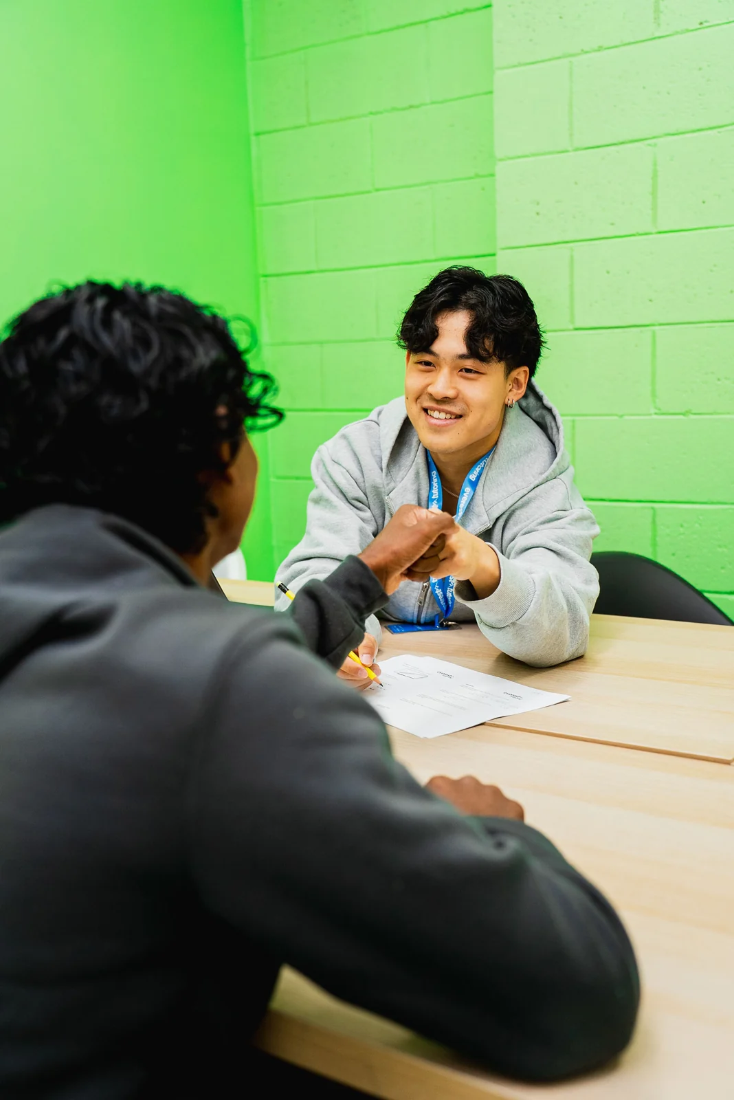 A student answering a station across the desk from a tutor