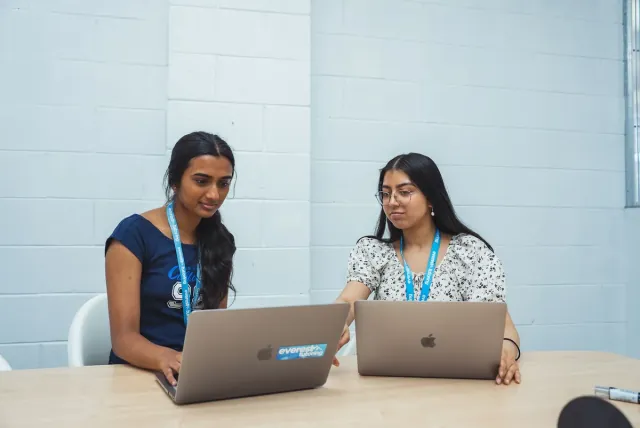 Two students reviewing their results on laptops